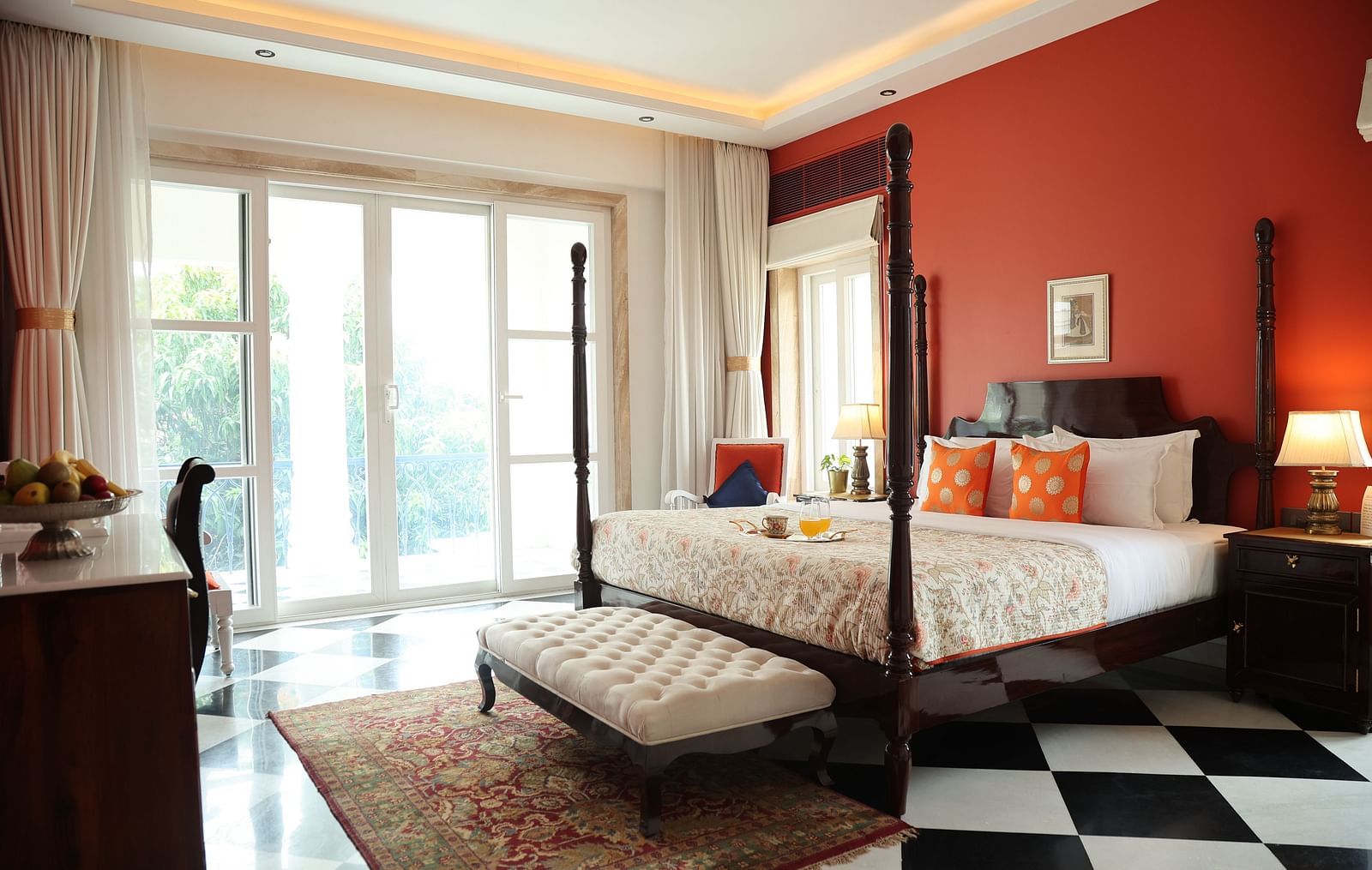 A room at Dileep Kothi, Jaipur with a double bed, side tables with night lamps, French windows, and chequered tiles